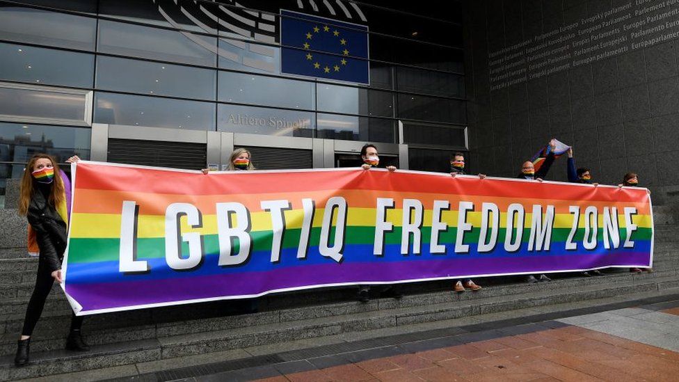 People outside the European Parliament holding a banner that says "LGBTIQ Freedom Zone"