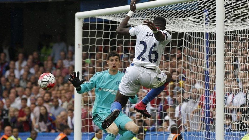 Crystal Palaces French Bakary Sako (R) passes the ball past Chelseas Belgian goalkeeper Thibaut Courtois for Crystal Palaces English defender Joel Ward (not pictured) to score his team"s second goal during the English Premier League football match between Chelsea and Crystal Palace at Stamford Bridge in London on August 29, 2015