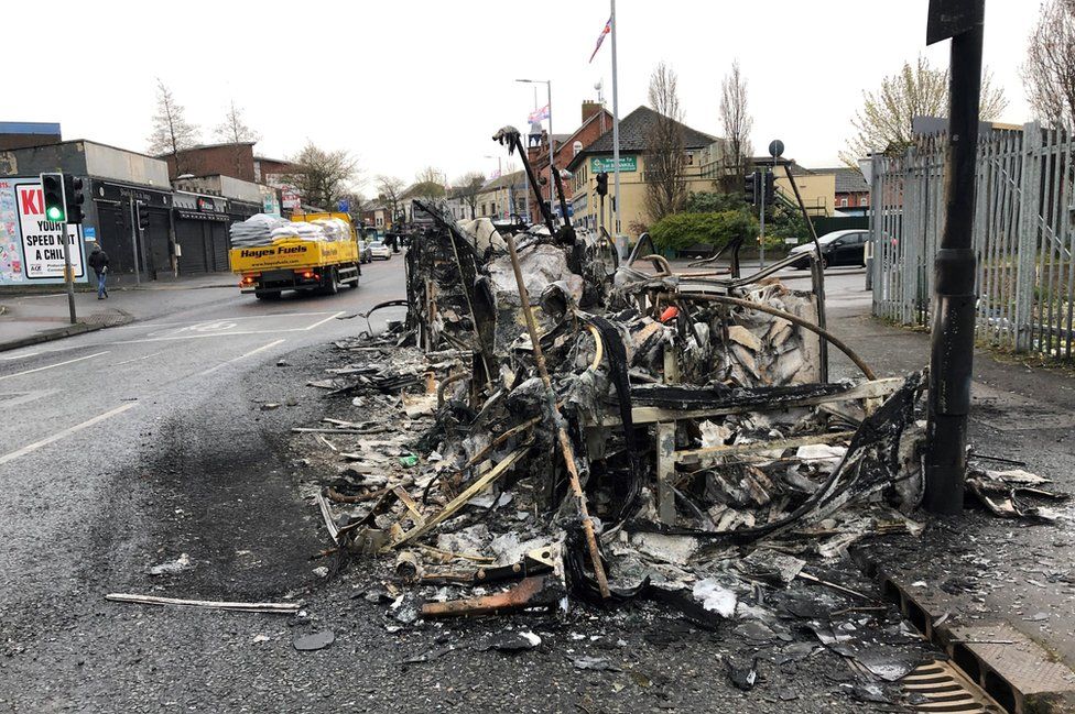 The burnt wreckage of a bus that was set on fire during rioting in west Belfast