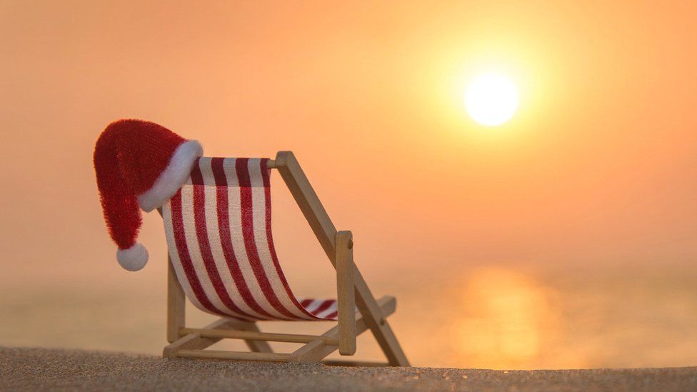 Deckchair with Christmas Santa hat at ocean beach during sunset