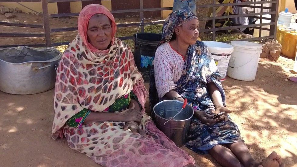 Women sitting next to buckets of water