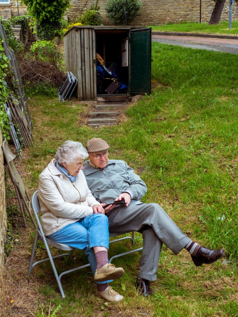 An elderly couple sat in a park. Wetherby, West Yorkshire.