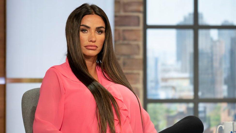 Katie Price sits in a pink chair wearing a pink shirt