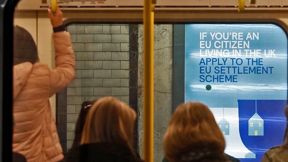 A poster advertising the UK's settlement scheme for EU citizens, seen through a Tube train