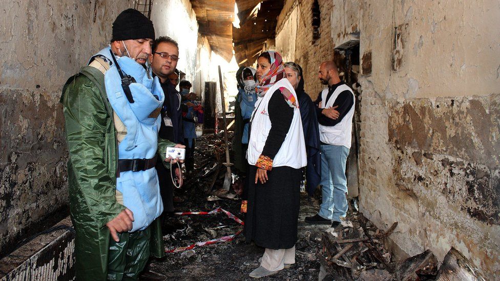 Workers stand in a charred corridor in the damaged hospital