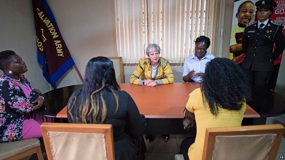 Theresa May speaks to two women at the Salvation Army headquarters in Lagos