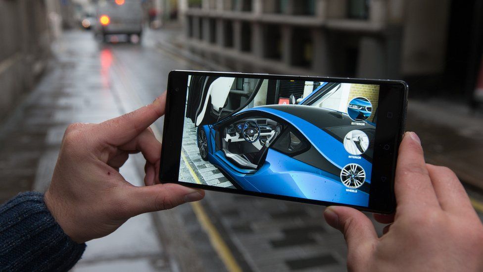 Man holding smartphone showing virtual BMW car in a street