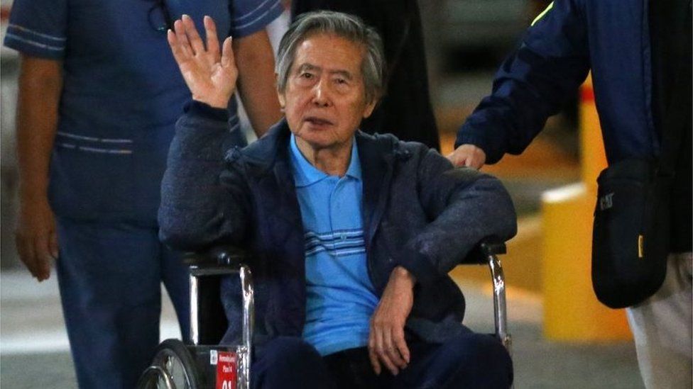 Peru"s former President Alberto Fujimori waves to supporters as he is wheeled out of the Centenario Clinic in Lima on January 04, 2018