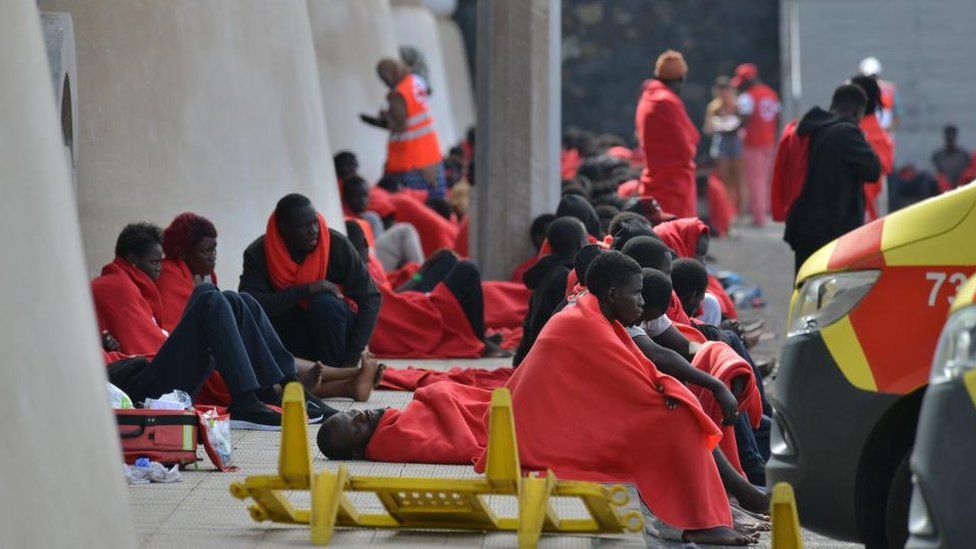 Some of those who arrived in El Hierro on Tuesday being treated by rescue workers. They are seen sat on the ground wrapped in red blankets.