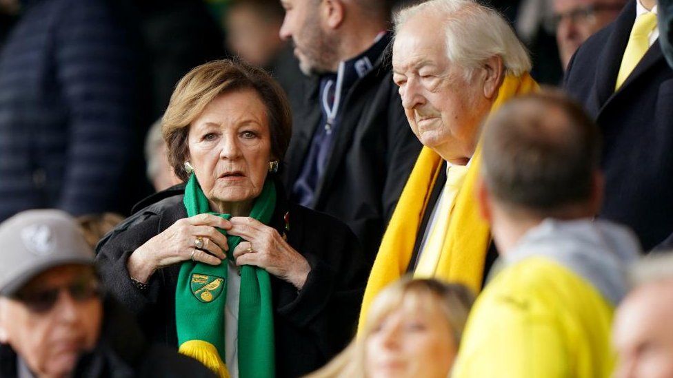 Woma wearing Norwich City scarf in a football stand