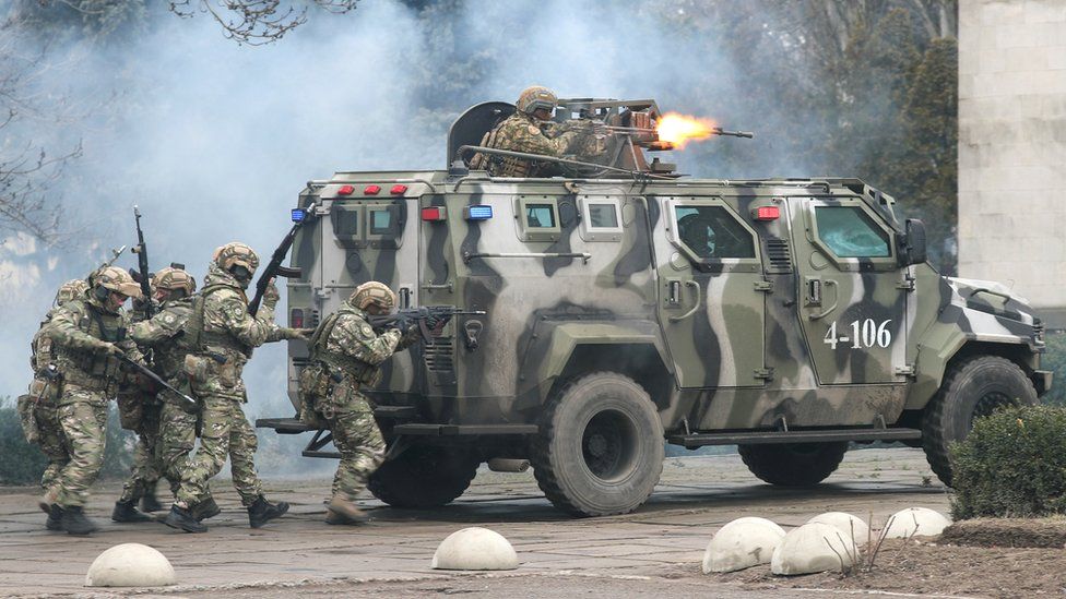 Troops rally behind a vehicle firing a mounted gun during training exercises