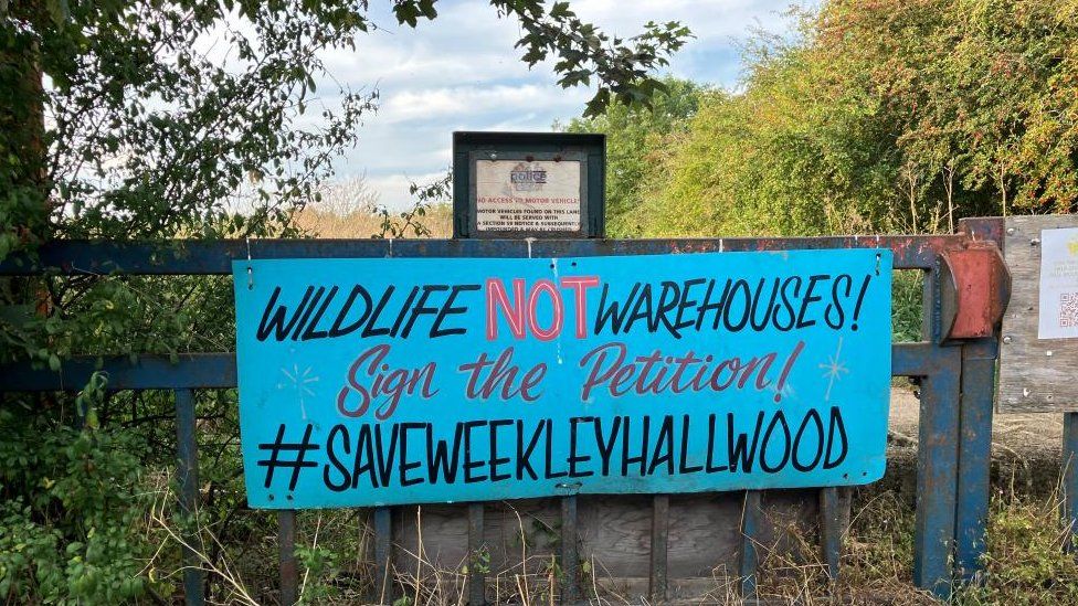 "Wildlife not warehouses" attached to fence on edge of wood