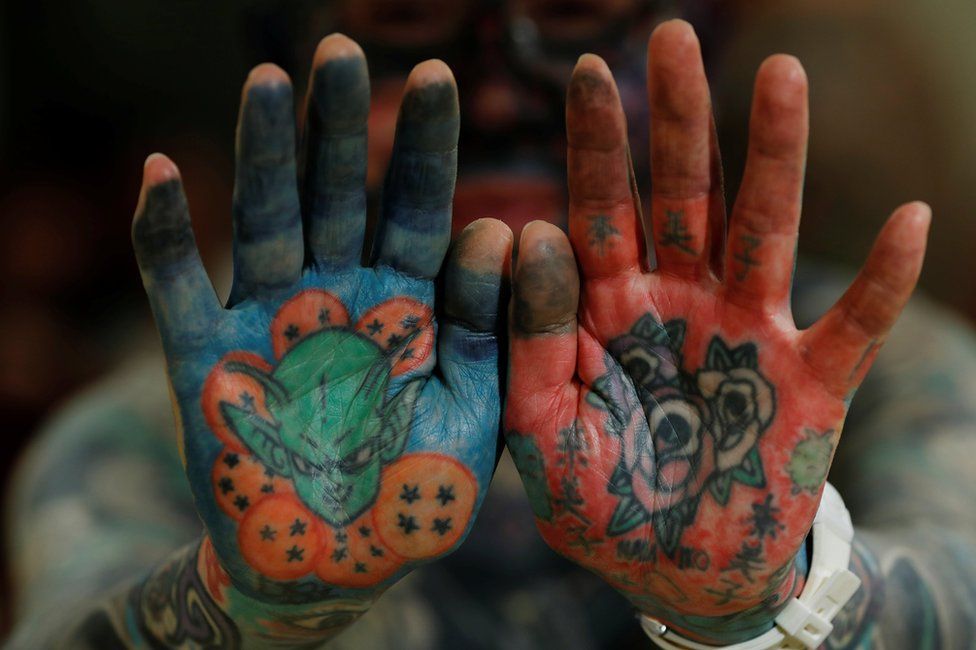 A man shows his tattooed palms to the camera