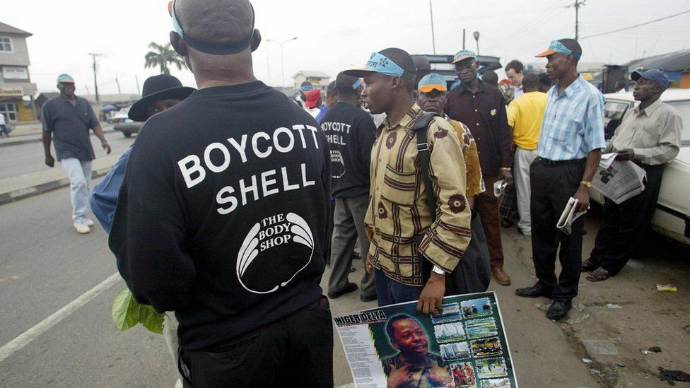 A man wearing a T-shirt advocating the boycott of Shell oil stands next to another carrying a poster of Ken Saro-Wiwa during a rally on the Port Harcourt highway 10 November 2005