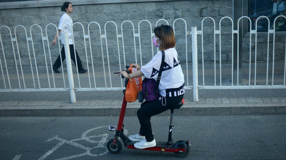 A Chinese woman drives an electric scooter along a street in Beijing