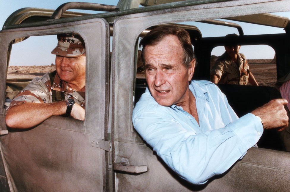 President George Bush and General Norman Schwarzkopf ride in a military vehicle in Saudi Arabia