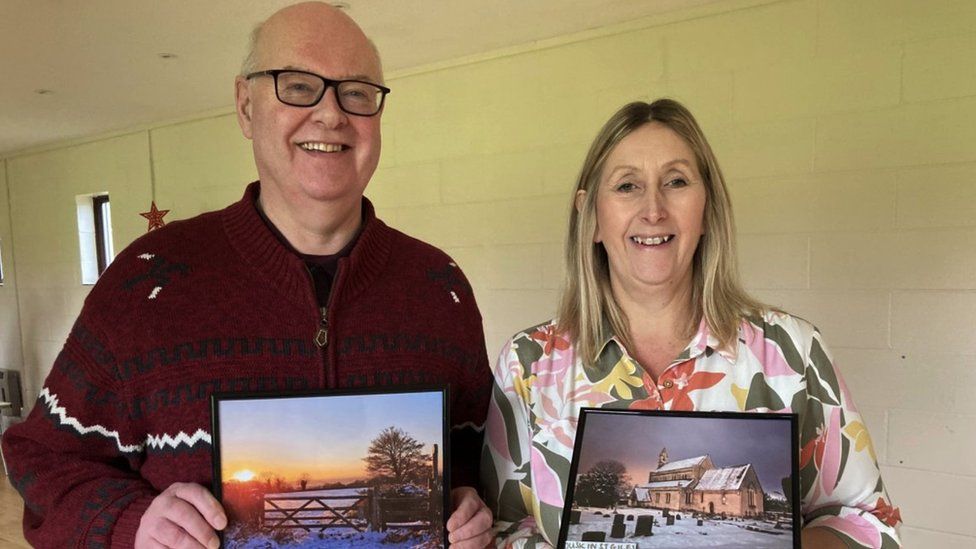 Michael de Graeve and Laura Cabry pictured with their winning photographs. Michael's photograph is of a gate which is covered in snow. There is a bright orange sunset in the sky. Laura's photograph is of a church, also covered in snow. The sun is setting in her image too.