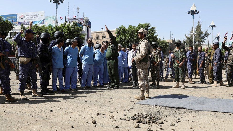 Военнослужащие хуситов стоят рядом с мужчинами, обвиняемыми в причастности к убийству лидера повстанцев за день до их расстрела в Сане, Йемен (18 сентября 2021 г.)