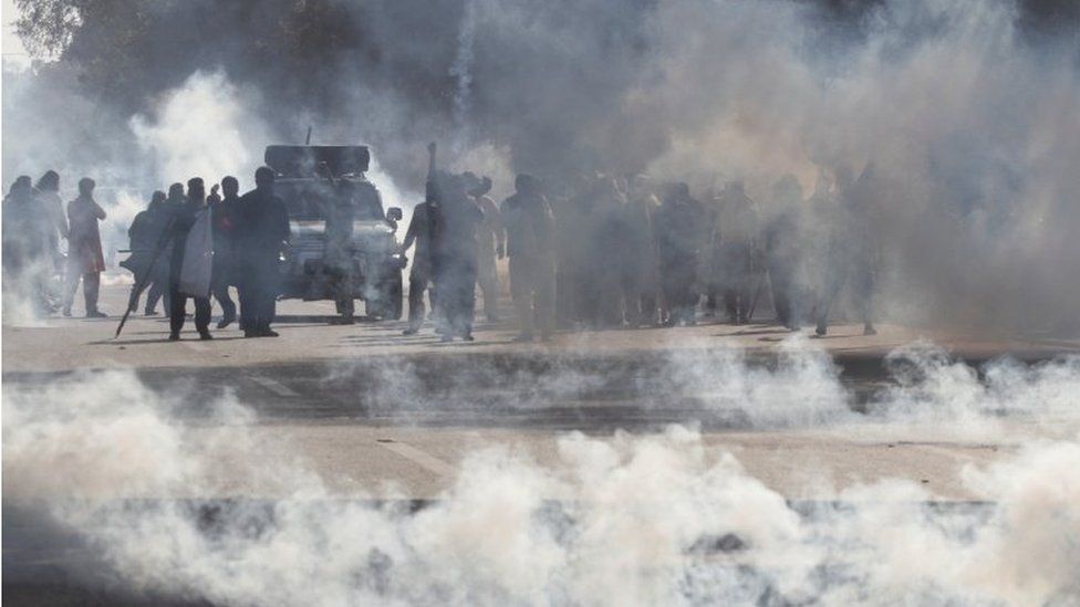 Supporters of former Prime Minister Khan, Imran, react amid tear gas smoke, fired by the police to disperse them during clashes ahead of an election campaign rally, in Lahore, Pakistan (March 8, 2023).