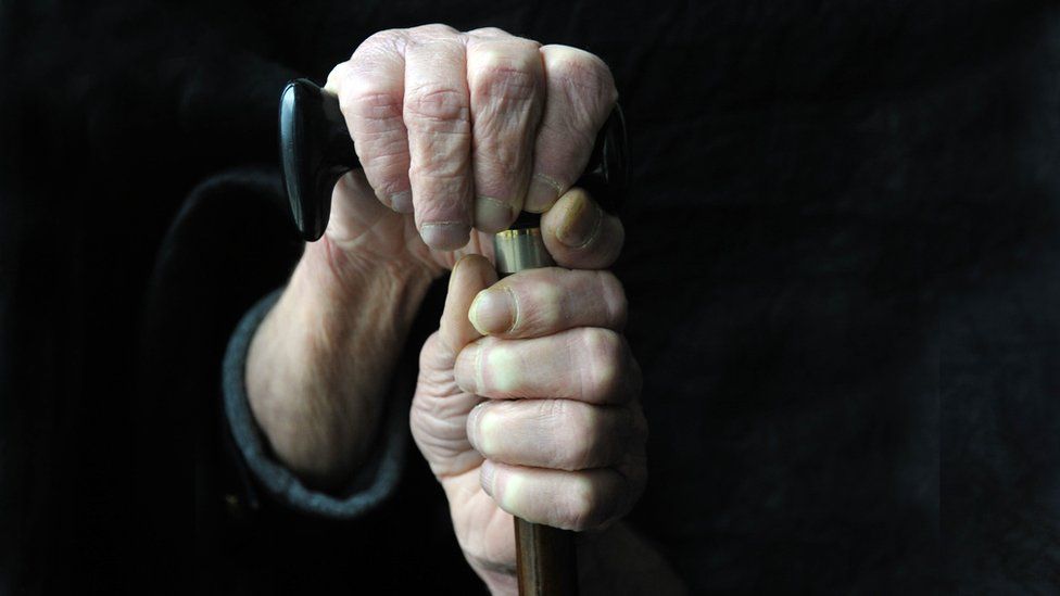 Elderly person holding onto walking stick