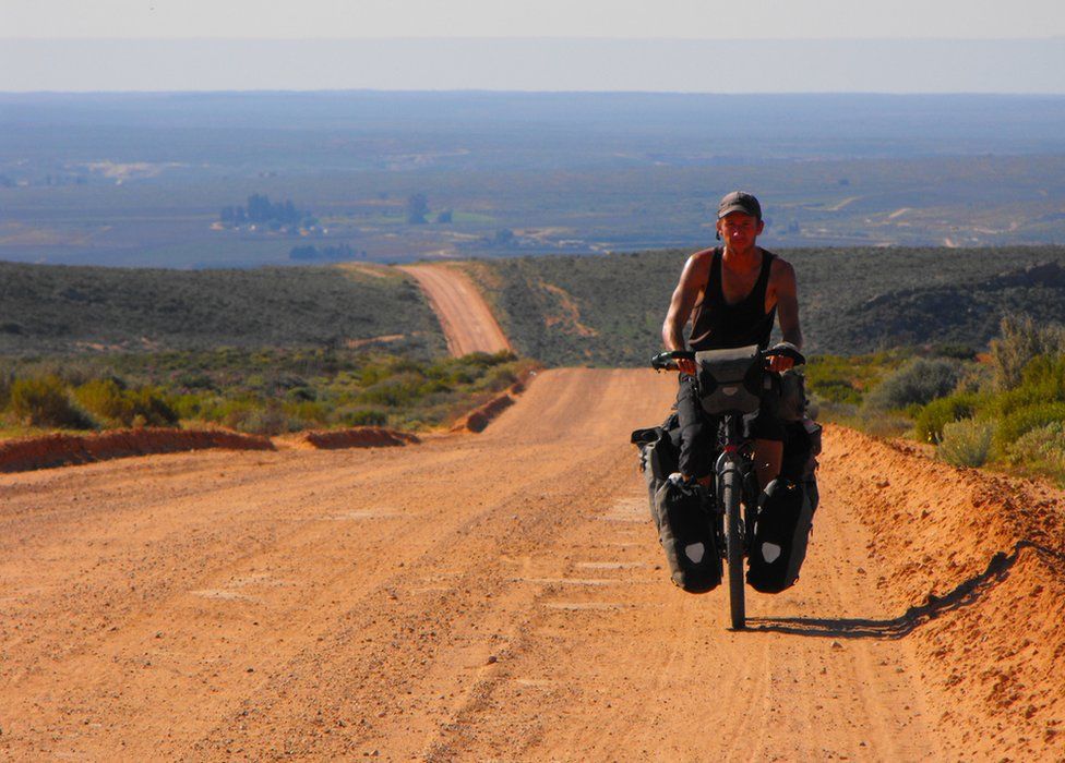 Cycling on a long red gravel road