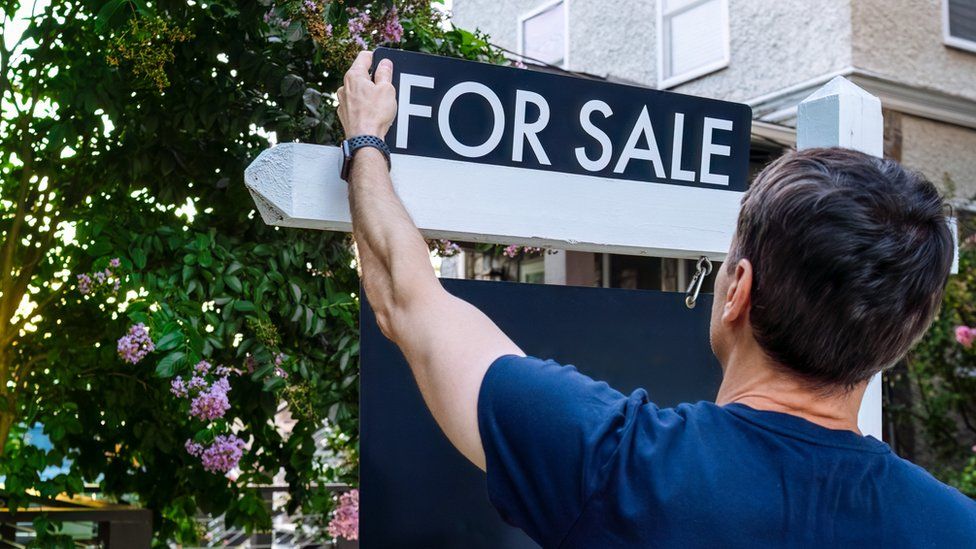 Estate Agent Adjusts For Sale Sign