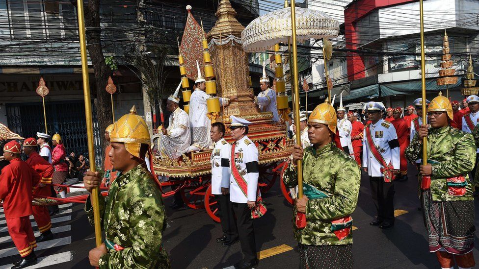 Men in ceremonial uniforms walk in a procession transporting the royal urn containing the remains of Thailand's most senior Buddhist monk, the late Supreme Patriarch Somdet Phra Nyanasamvara