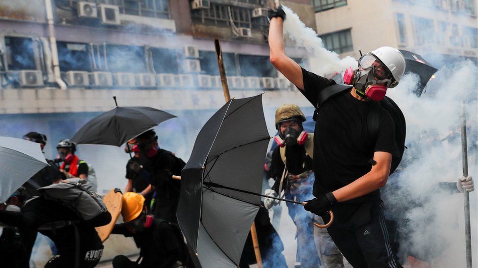 Демонстрант отбрасывает баллончик со слезоточивым газом во время столкновения с полицией по охране общественного порядка во время акции протеста в Гонконге, 24 августа 2019 г.