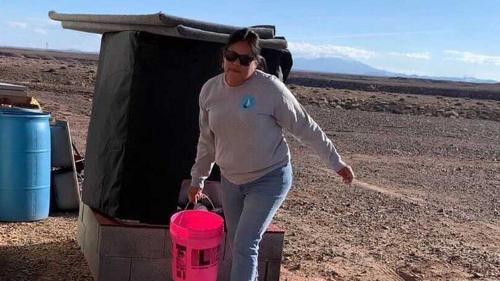 Shanna Yazzie fills a bucket of water from the local water tank