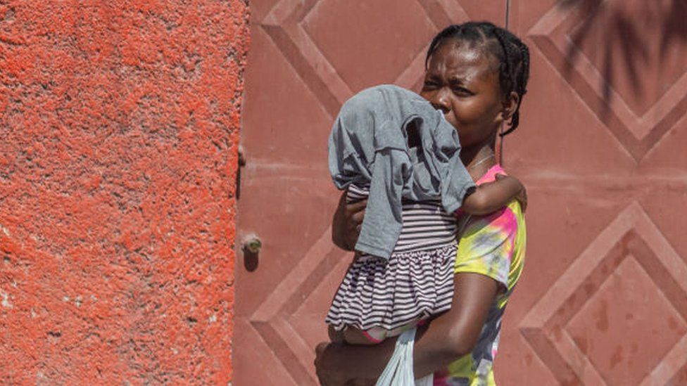 A woman passes with a child in her arm in the street of Port-au-Prince, Haiti, April 9, 2024.