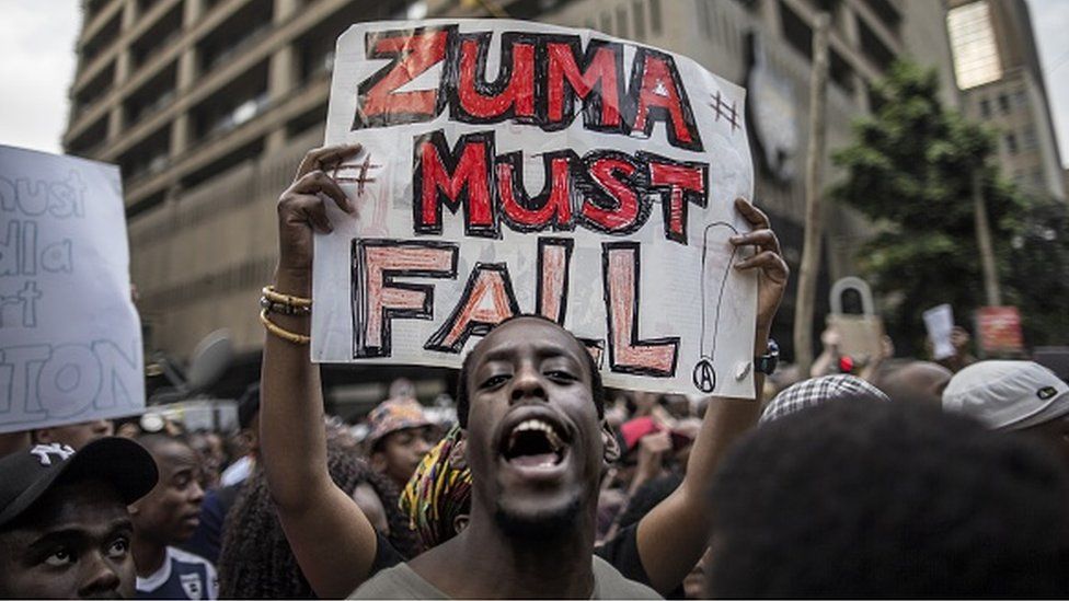 A student holds a placard reading 'A placard with 'Zuma must fall' outside the Luthuli House, the ANC headquarters, on October 22, 2015, in Johannesburg