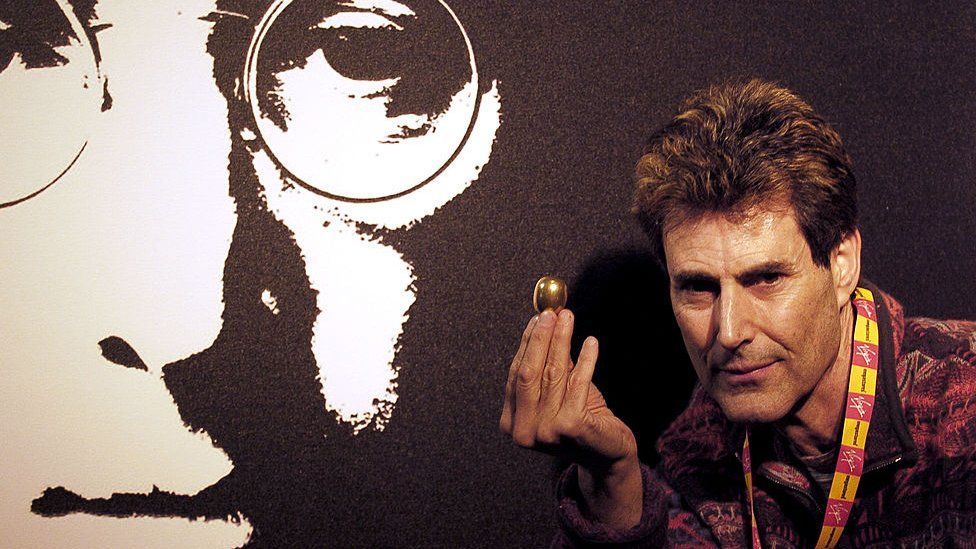 Ури Геллер с предметом в форме яйца перед портретом Джона Леннона (2005)