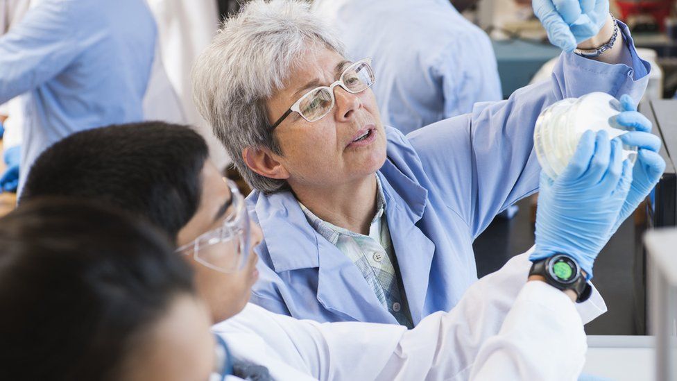 Teacher and students working in science lab - stock photo