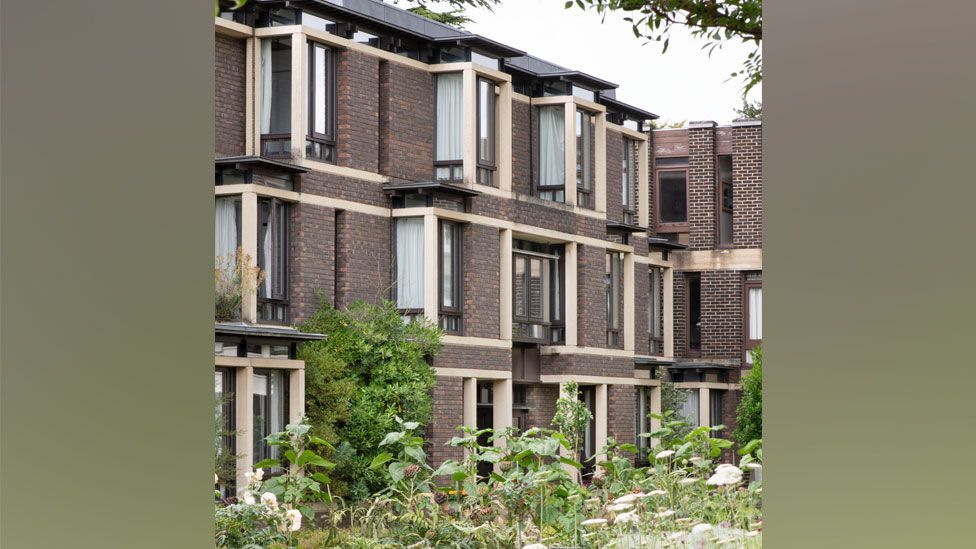 A three storey 1980s college building of red brick and stone with plants in front, Fitzwilliam College, Cambridge