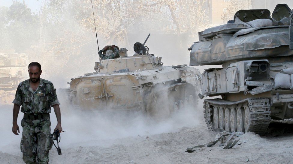 A Syrian army soldier walks past tanks in the Jobar neighborhood of Damascus, Syria, in 2013