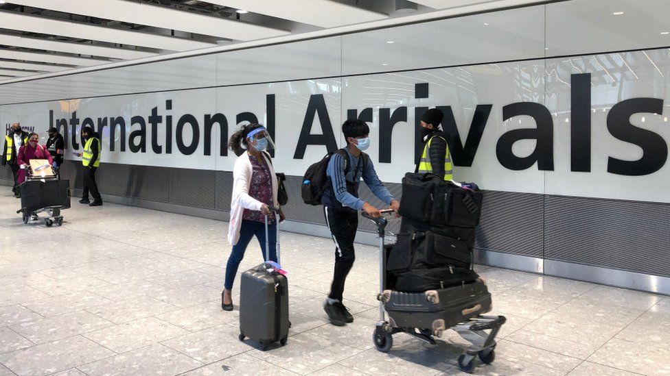 Люди с чемоданами в терминале прилета аэропорта Хитроу