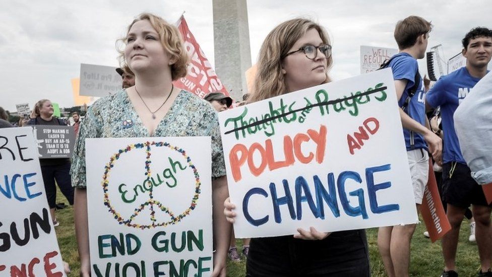 Demonstrators hold signs at 