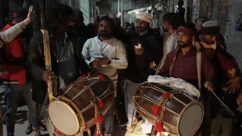 Men carrying large drums as part of Christmas carol procession