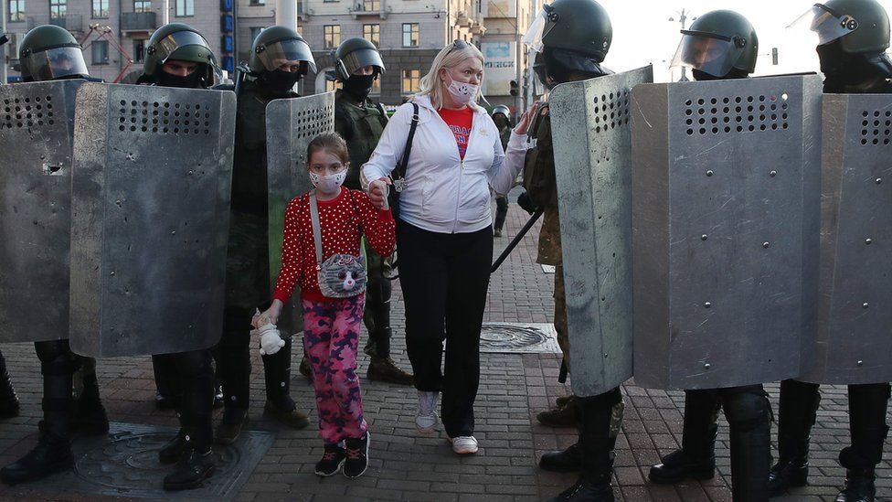 A woman with a child talks to riot police officers blocking an area during a rally in Independence Avenue on 20 September