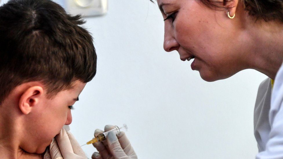 A child receives a vaccination against measles, 16 April 2018