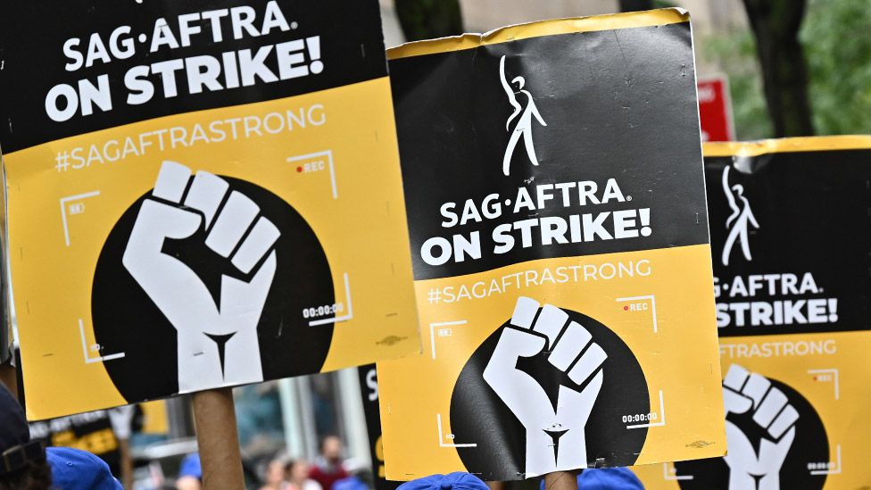 People holding up placards saying "Sag-Aftra on strike"