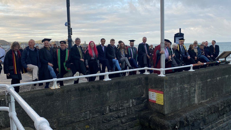 people standing in row on seafront