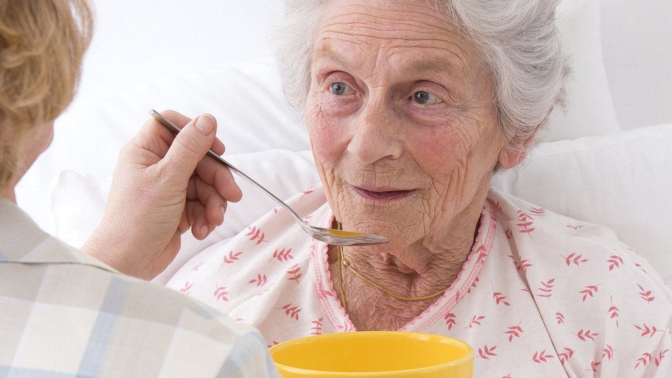 Old woman being fed