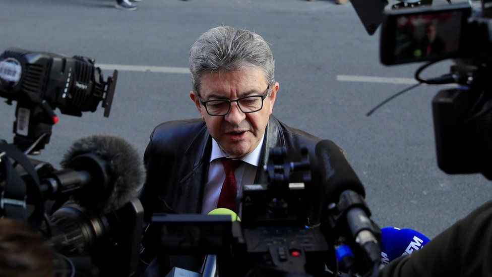 Jean-Luc Mélenchon is pictured surrounded by cameras in a press huddle on a street
