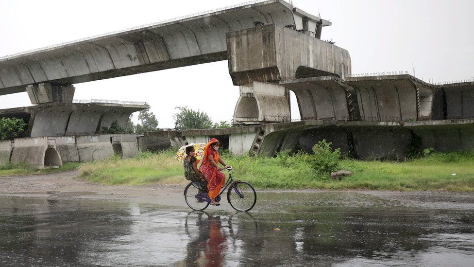 A woman on a bicycle rides in heavy rain