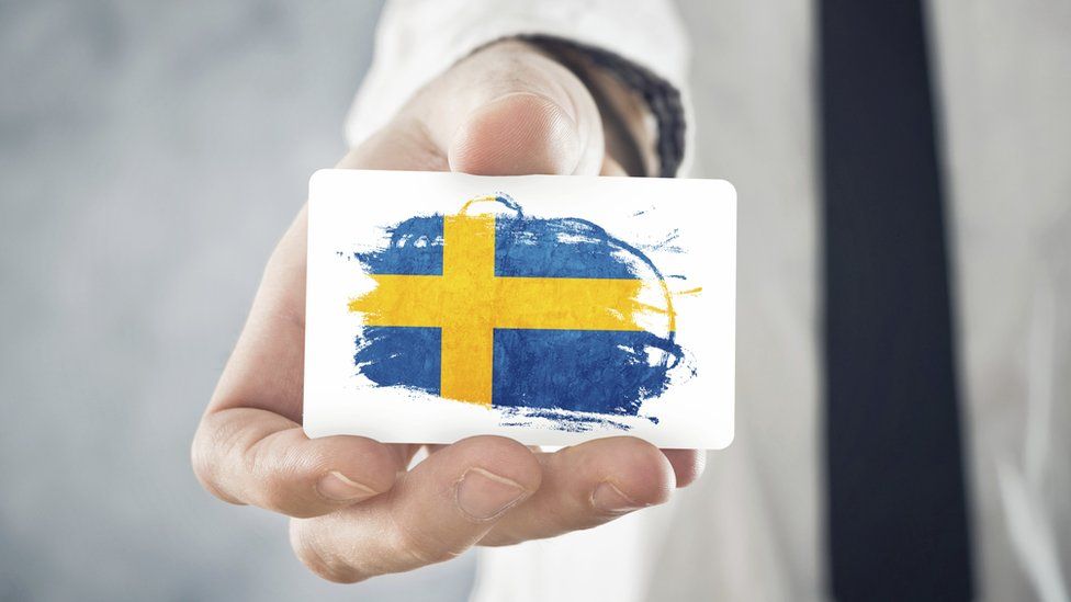 Man holding business card with Swedish flag