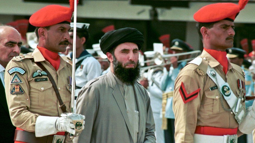 Gulbuddin Hekmatyar, centre, passes in front of an honour guard in the Afghan capital of Kabul (26 June 1996)