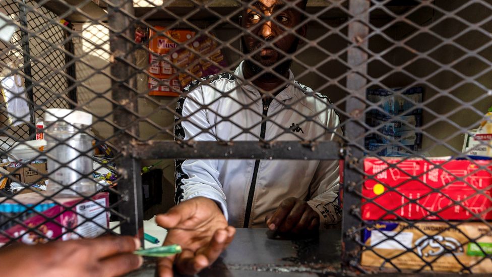 Гетачью Деста за клеткой в ​​своем магазине в поселке Александра, Йоханнесбург, Южная Африка