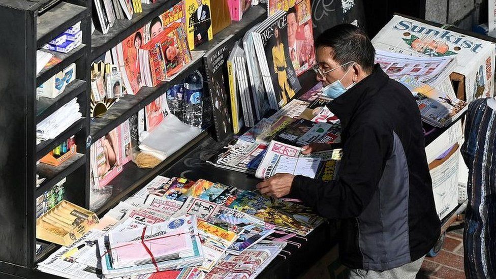 A seller sorts newspapers at a newsstand in Hong Kong