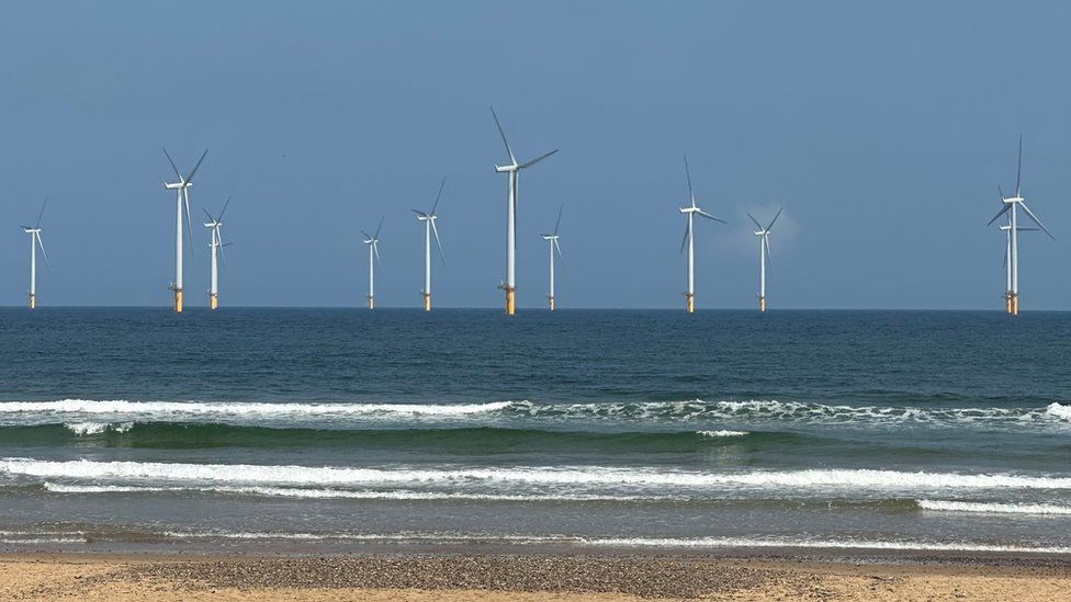 Wind turbines out at sea pictured from a beach